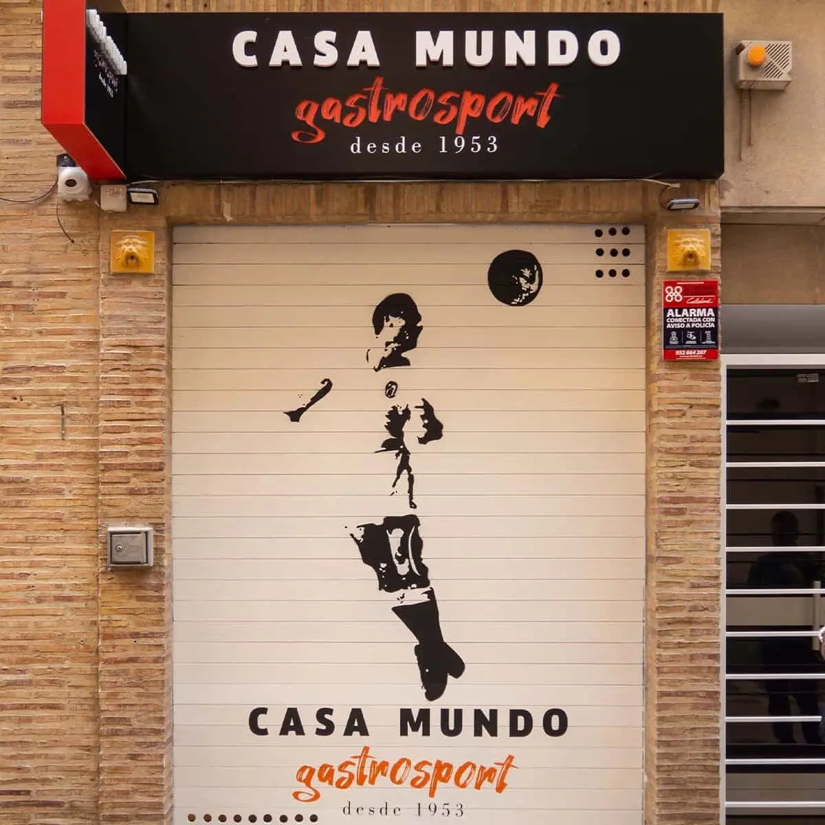 mural sobre persiana de negocio de un futbolista en negativo rematando de cabeza